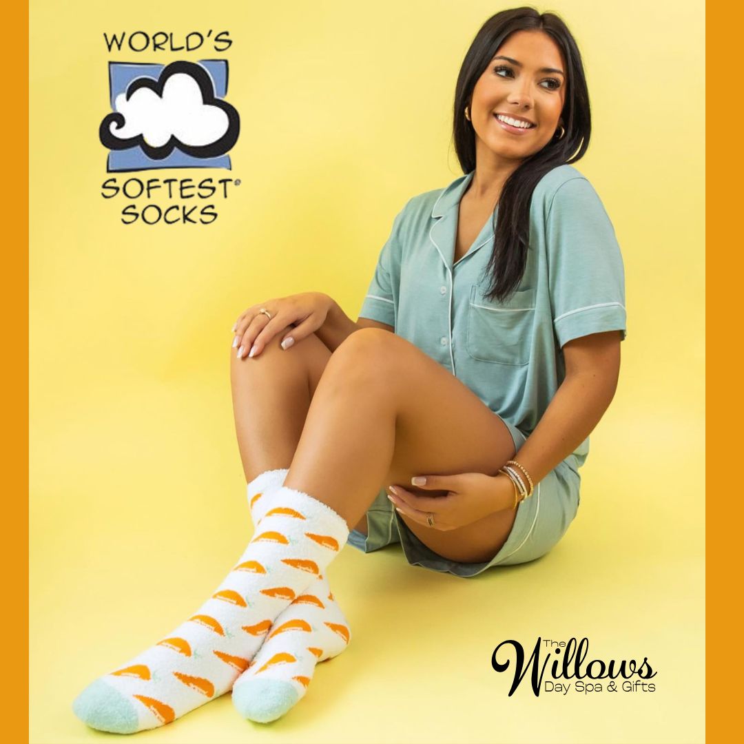 woman in her 20's wearing pajamas and a pair of white socks with mint green toe and orange carrots on the socks