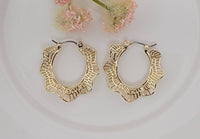 Gold hoop earrings on a light background with pink flowers.