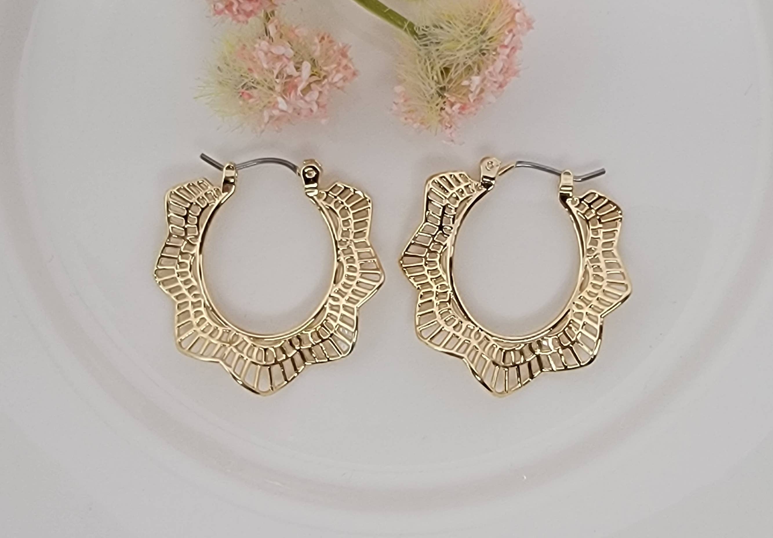 Gold hoop earrings on a light background with pink flowers.