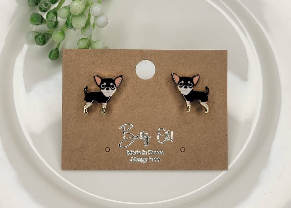 Pair of chihuahua-shaped earrings on a brown card with 'Bobby Oll' branding.