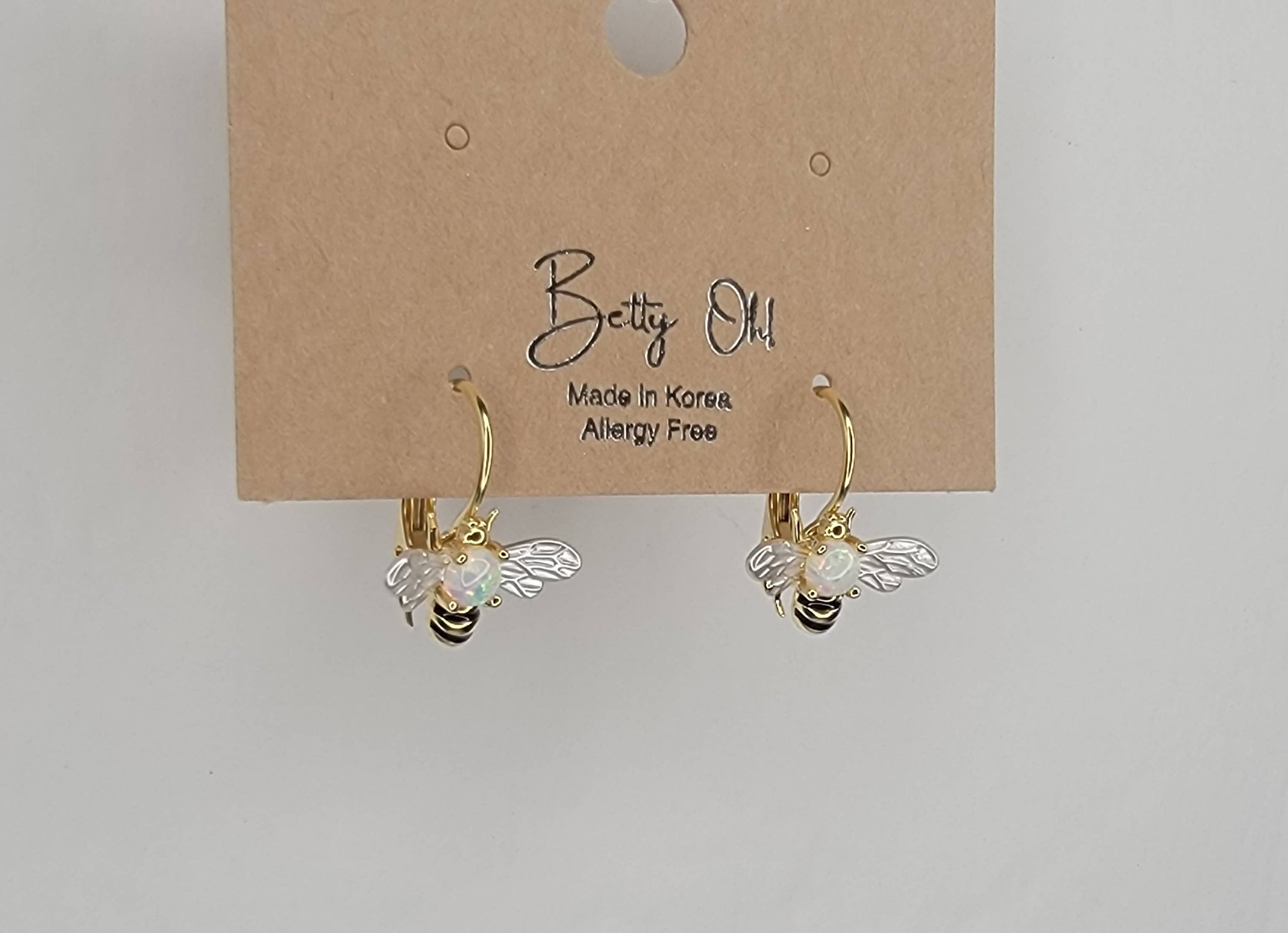 Bee-shaped earrings on a 'Betty Old' branded card against a light gray background