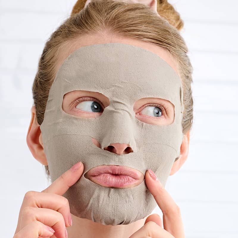 Person wearing a beige face mask against a white background