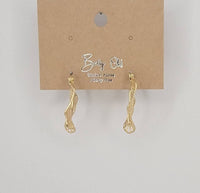 Gold earrings on a brown card with 'Betty Old' branding against a light gray background