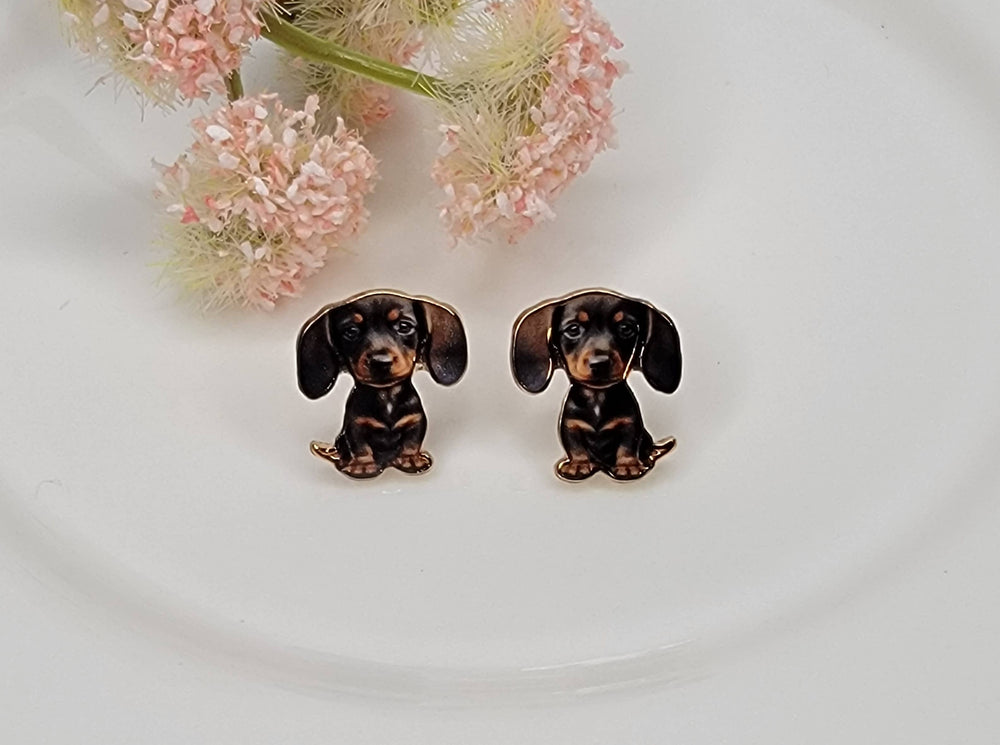Pair of dachshund-shaped earrings on a white background with pink flowers.