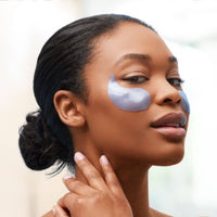 Woman applying eye patches under her eyes with a blurred background