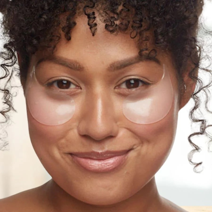 Woman wearing clear eye patches on a neutral background
