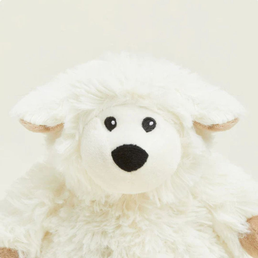 Plush toy sheep with black eyes and nose on a light beige background