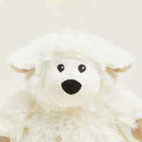 Plush toy sheep with black eyes and nose on a light beige background