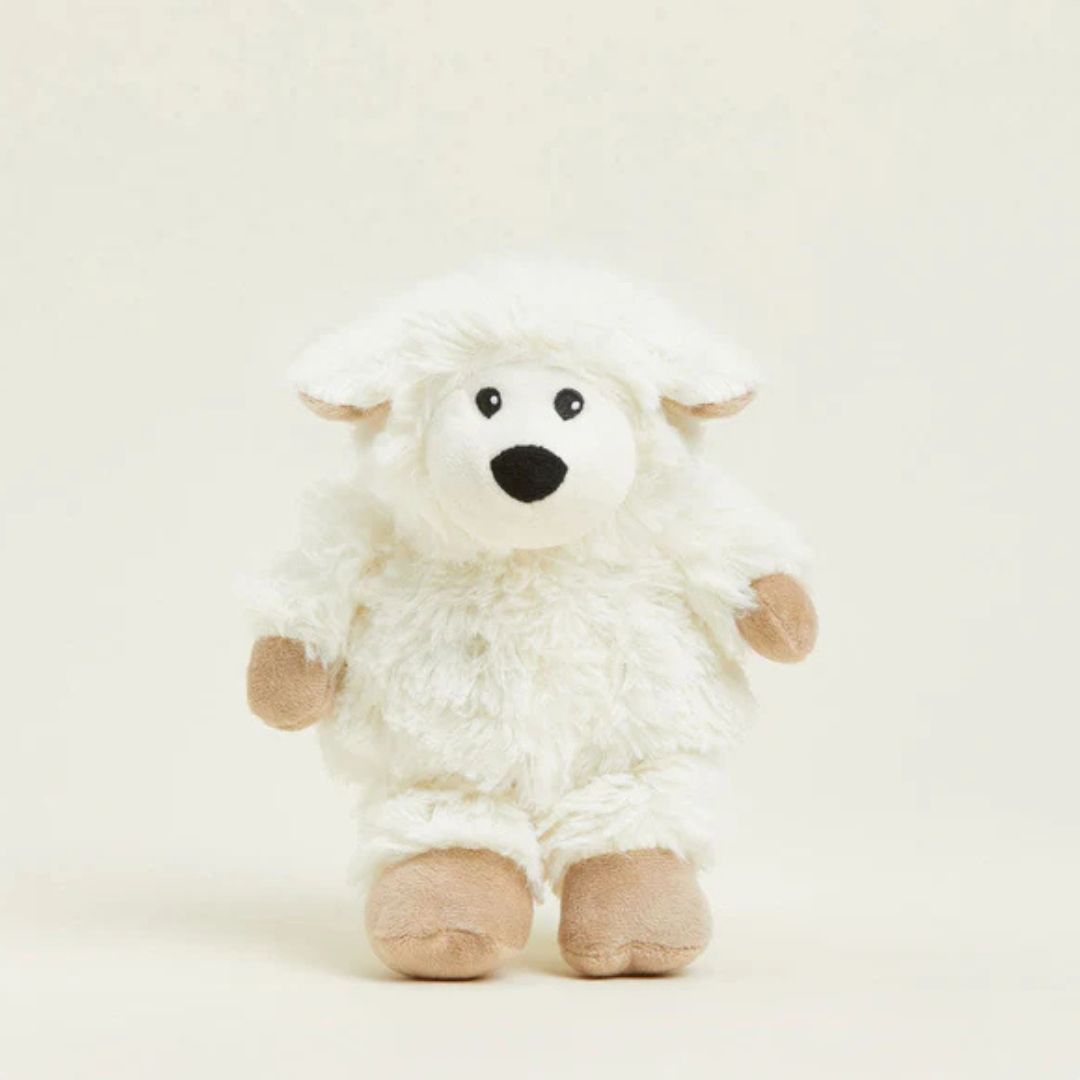 White plush sheep toy with brown feet on a beige background